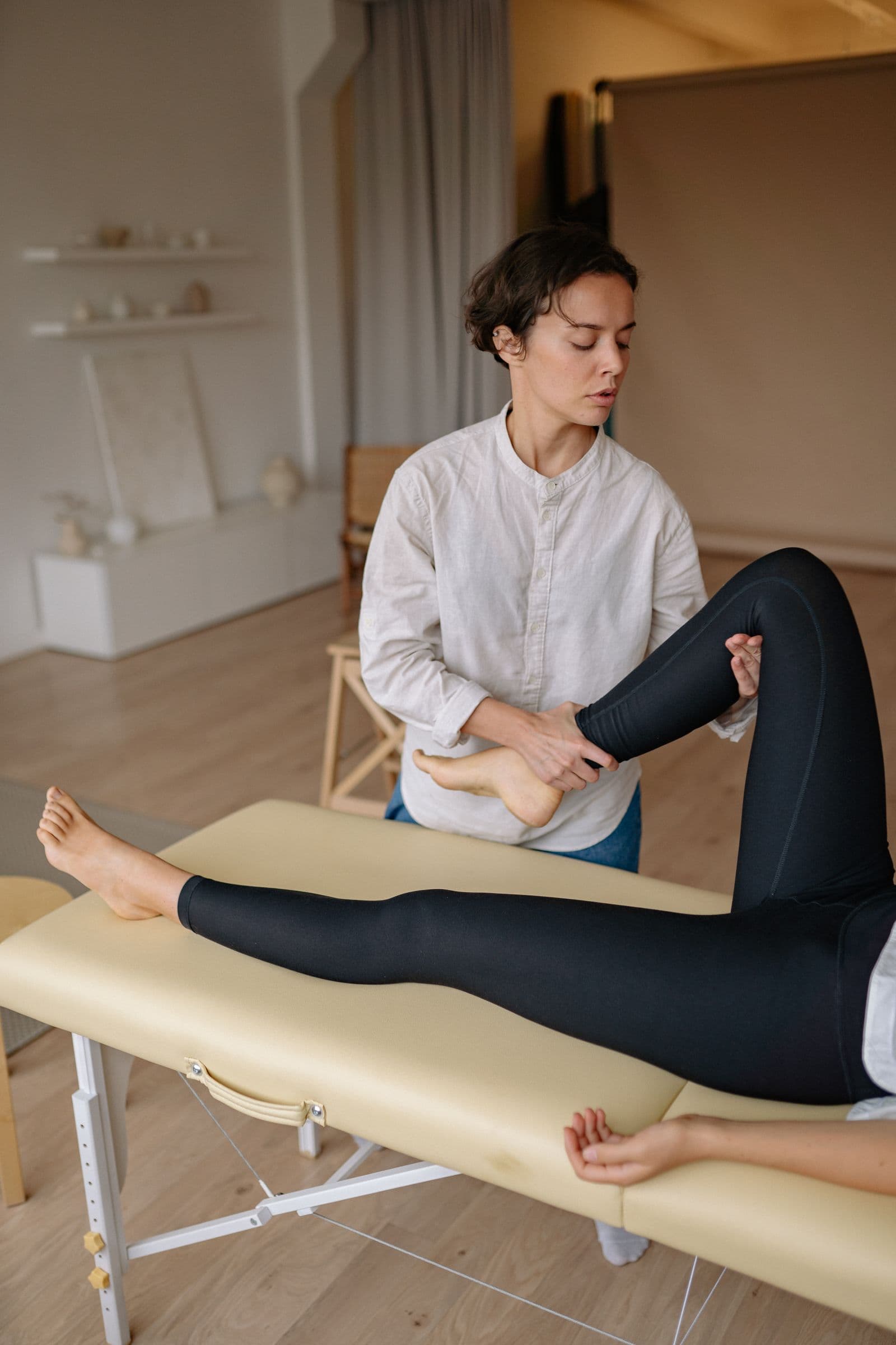 Fizioterapeut care evaluează flexibilitatea și forța musculară a piciorului unui pacient