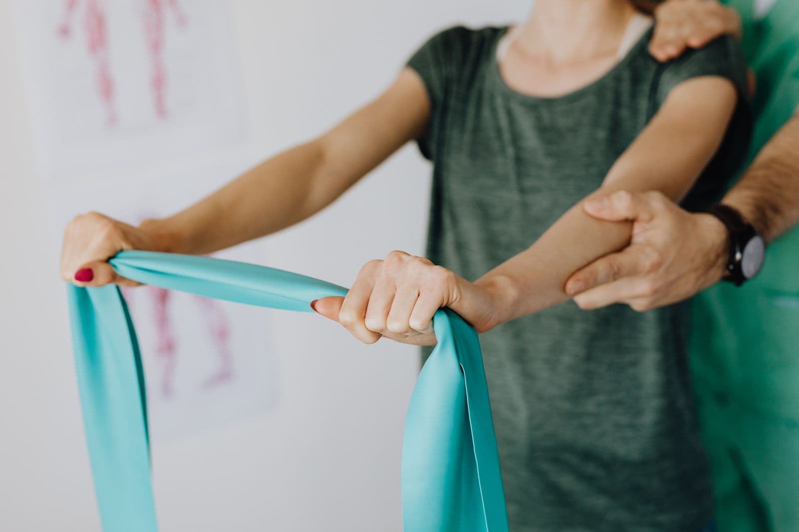 Terapeut care sprijină brațul unui pacient în timpul unui exercițiu cu bandă elastică pentru umăr