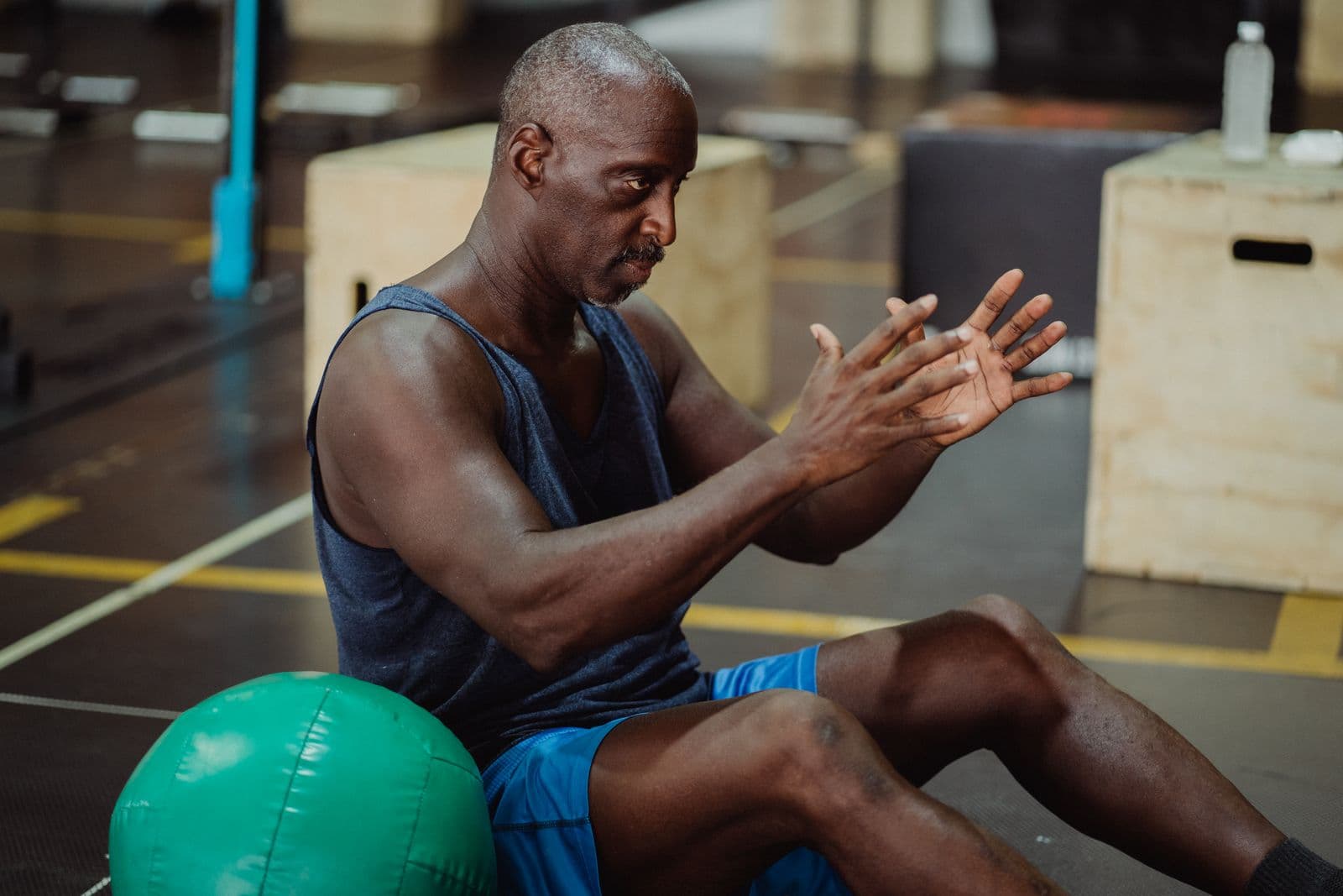 Sportiv care execută un exercițiu de forță cu mingea medicinală, în sala de sport