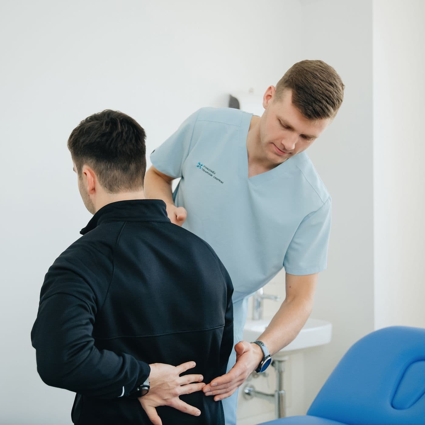 Fizioterapeut care evaluează zona lombară a unui pacient