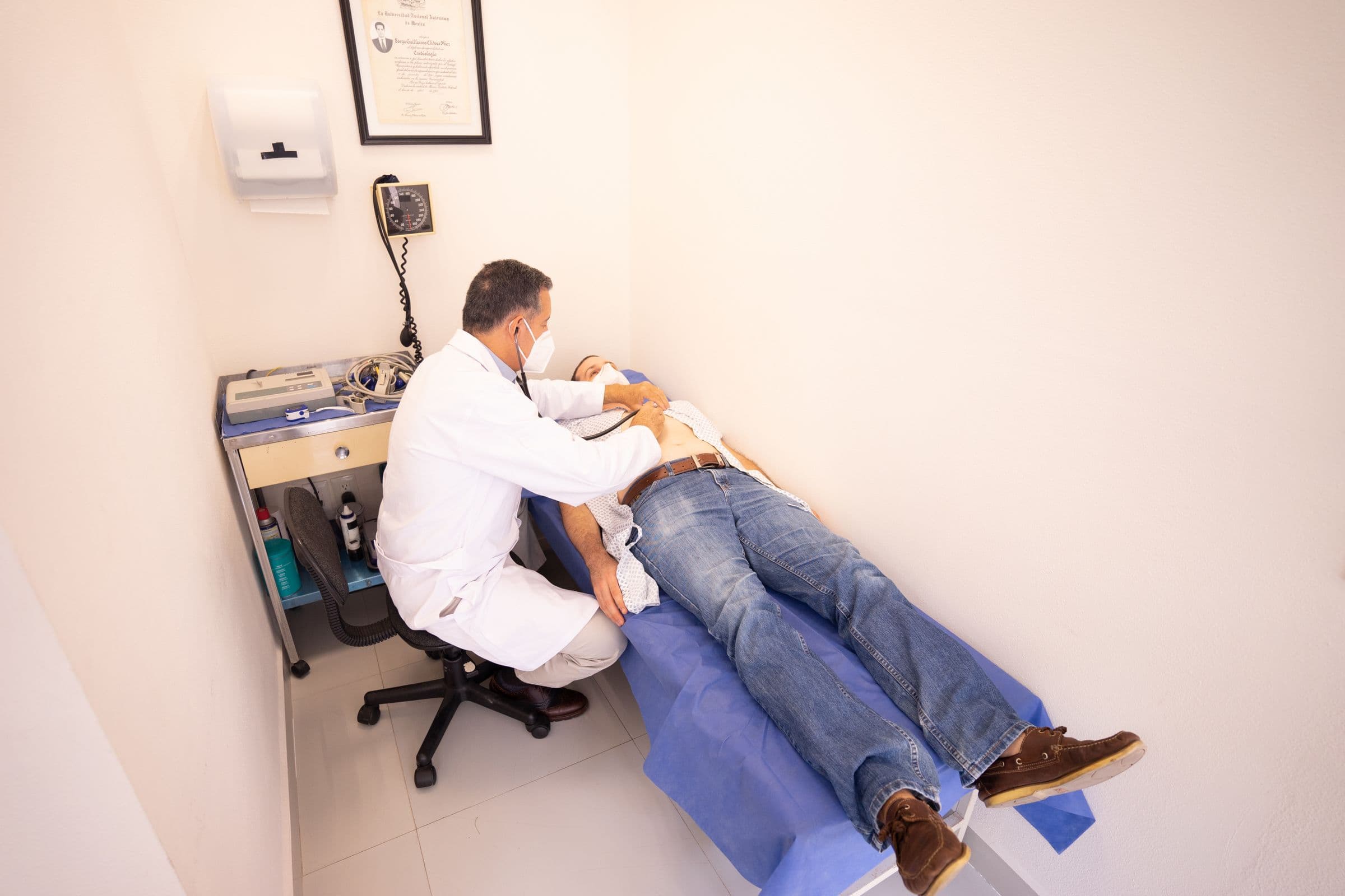 Medic care examinează un pacient întins pe canapeaua de consultație