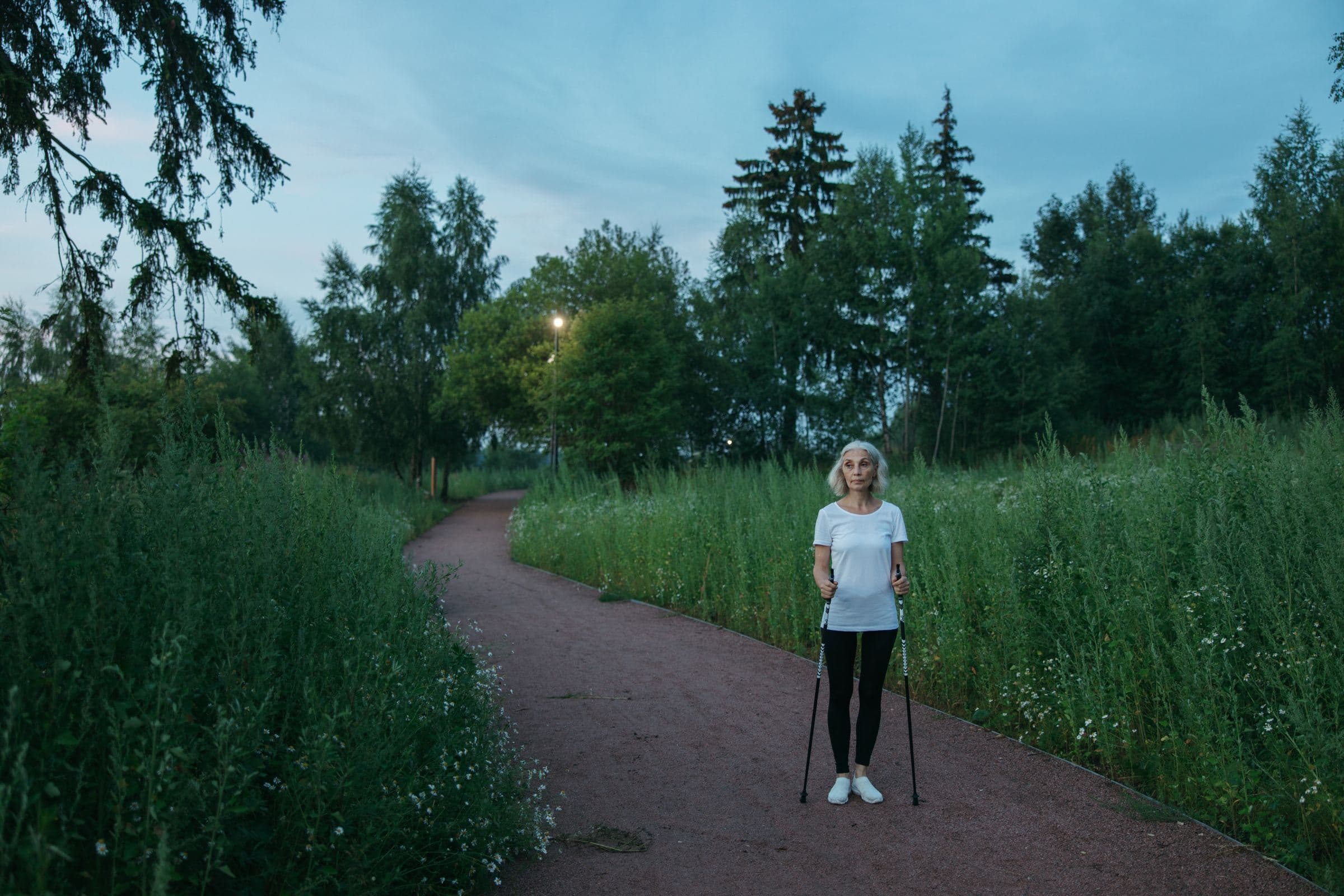 Femeie care face mers nordic pe o alee dintr-un parc
