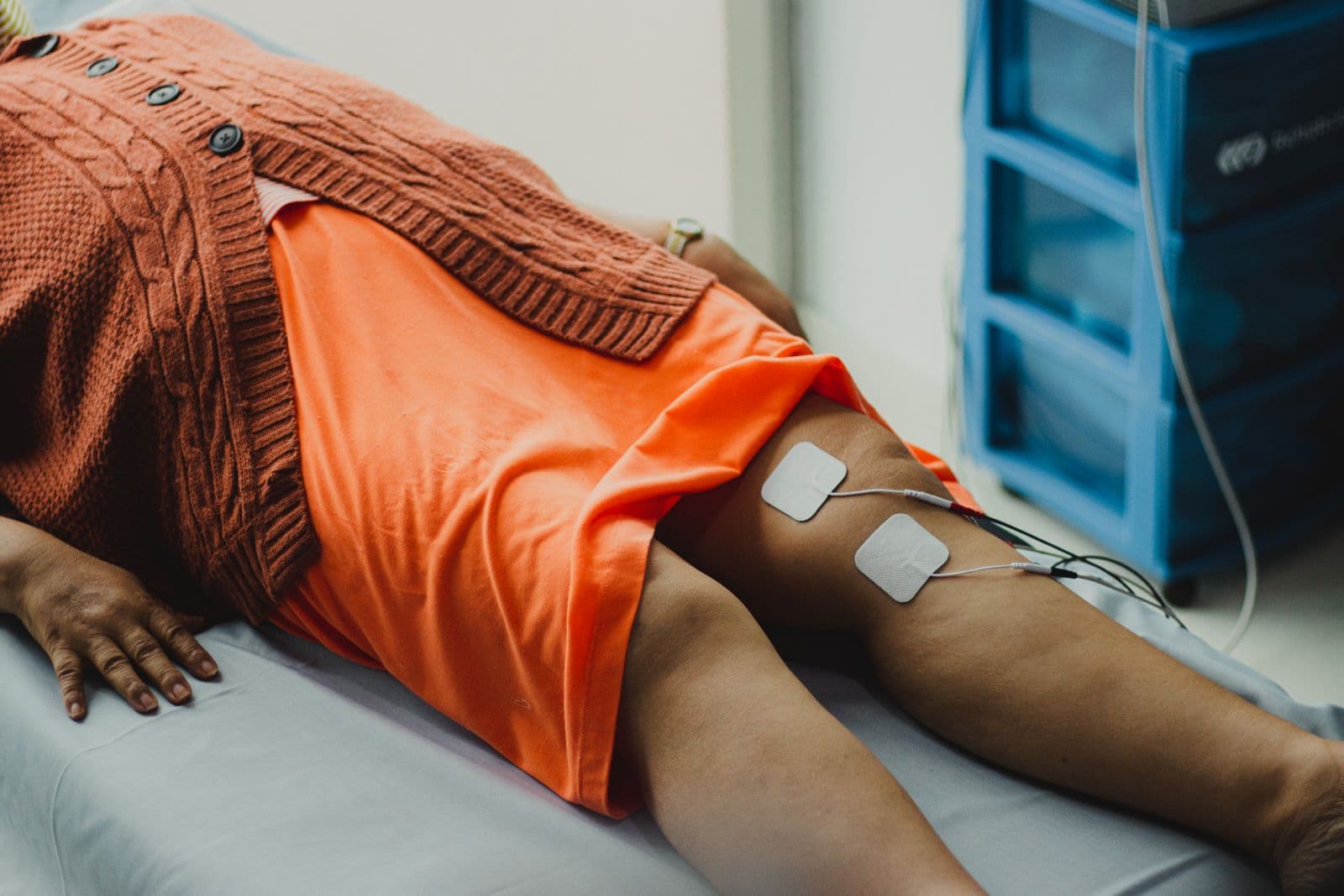 Electrozi de electroterapie aplicați pe zona genunchiului în cadrul unei ședințe de recuperare